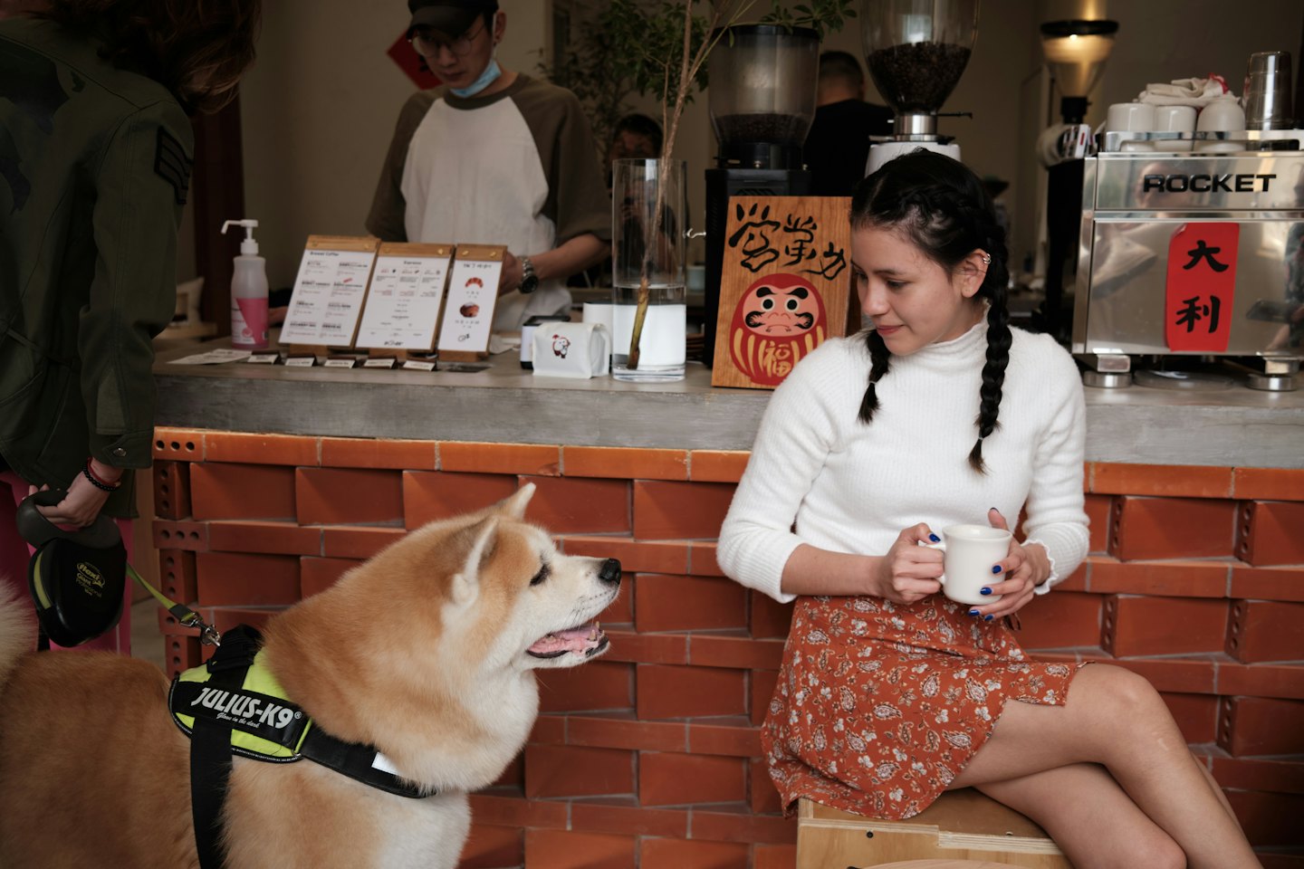 Woman sits on a stool and smiles at an Akita dog.