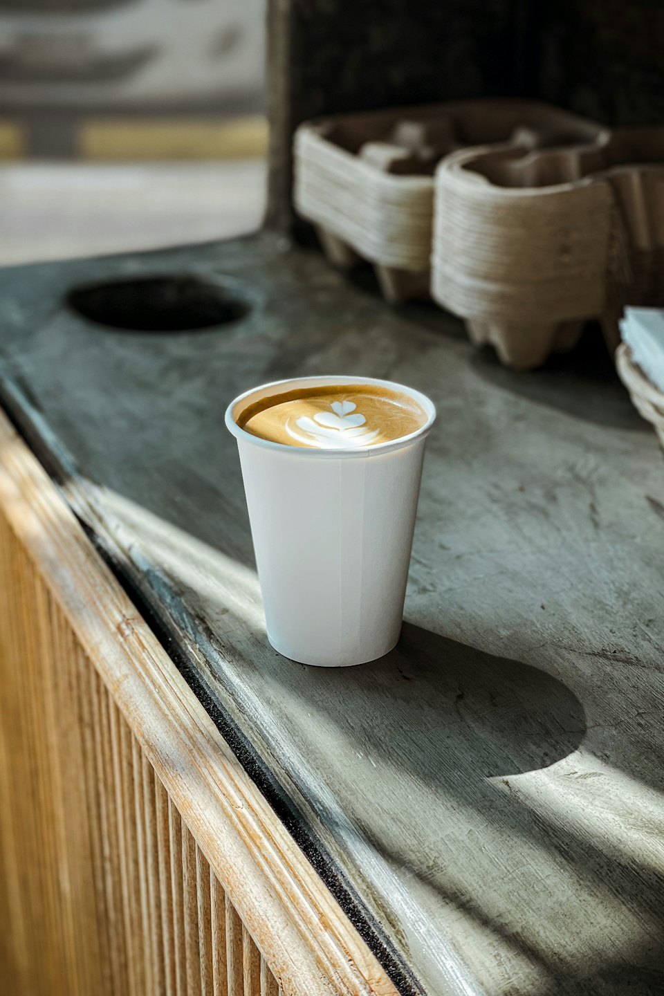A latte with heart art sits on a rustic counter.