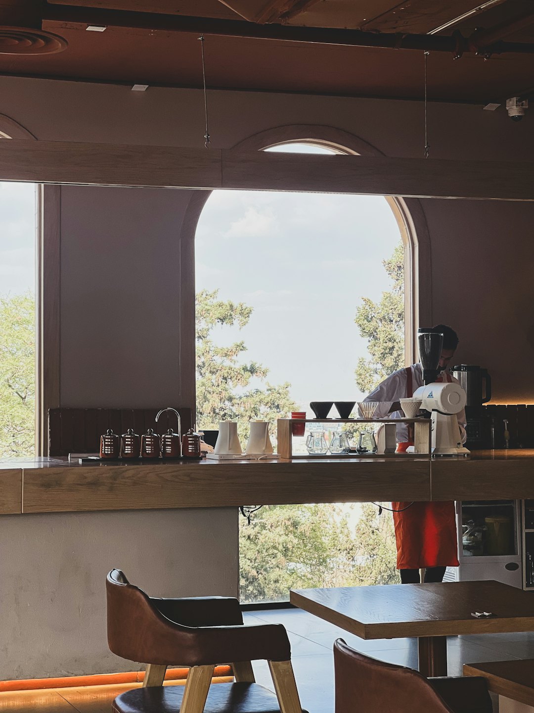 A barista prepares coffee behind a wooden cafe counter.